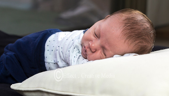newborn baby lying on a cushion